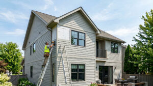 Man on a ladder install vinyl siding on a home